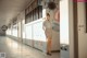 A woman in a white shirt and gray skirt standing in a hallway.