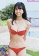 A woman in a red bikini posing by a pool.