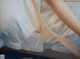 A woman in a white dress is holding a white sheet.