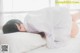 A woman laying on a bed under a white sheet.