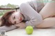 A woman laying on the ground next to a green apple.