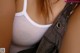 A close up of a woman wearing a white tank top.