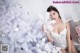 A woman in a white lingerie sitting next to a white Christmas tree.