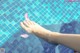 A person's foot in a swimming pool with a pink flower.