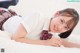 A young girl in a school uniform laying on a bed.