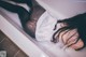 A woman laying in a bathtub with her back to the camera.