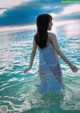 A woman in a blue dress standing in the water.