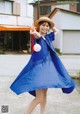 A woman in a blue dress and straw hat posing for a picture.