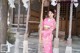 A woman in a pink kimono standing on a swing.