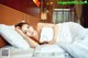 A woman laying on a bed with white sheets and pillows.